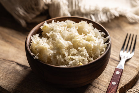 Fermented cabbage in a bowl on wooden cutting board.の写真素材