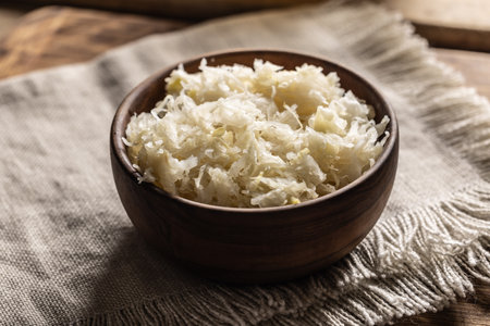 Fermented cabbage in a bowl on wooden cutting board.の写真素材