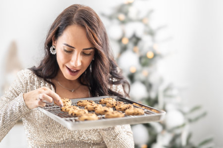 Woman takes hot Christmas cookies straight out of the baking tray while it is still hot.の写真素材
