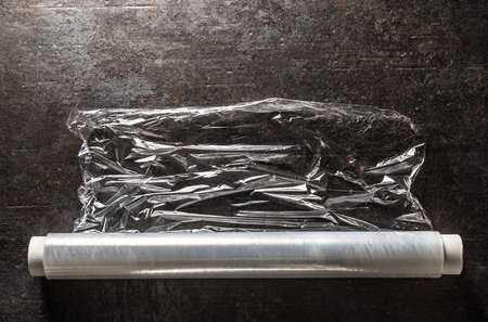 Roll of white wrapping plastic stretch film on dark concrete table.の写真素材