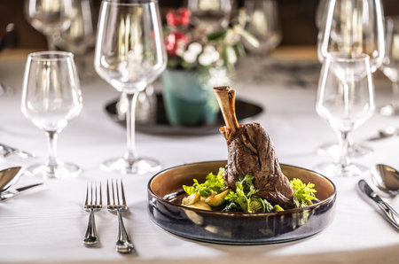 Confit leg of lamb on mashed potatoes with creamy kale, demi glace sauce and herbs in the hotel restaurant.の写真素材