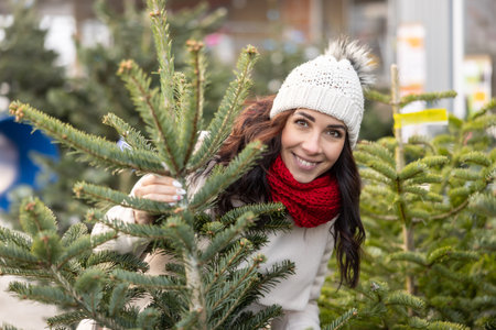 A smiling young woman among the Christmas trees at the market.の写真素材