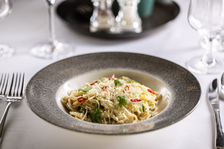 Italian Spaghetti Algio e Olio with Garlic Parmesan and chili peppers on restaurant festive table.の写真素材