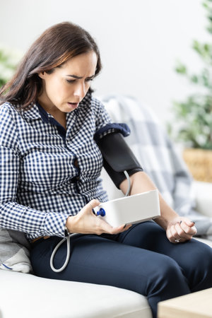 Frightened woman after measuring blood pressure with a measuring device because of a bad result.の写真素材
