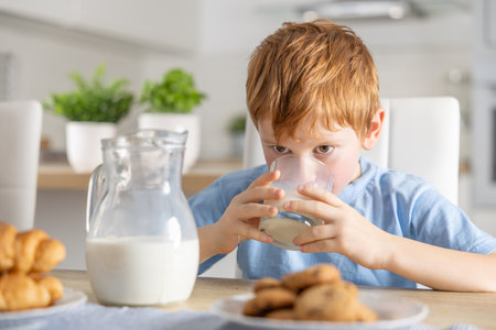 Cute boy drinks fresh milk for breakfast.の写真素材