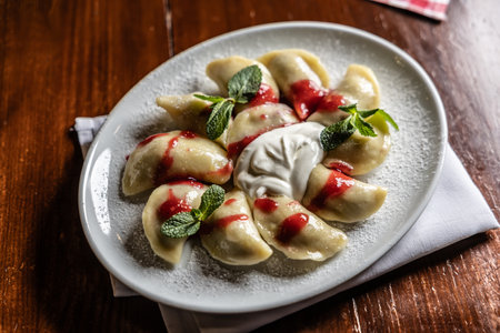 Eastern European traditional food dumplings - pierogi, varenyky, pirohy filled with strawberries and topped with jam.の写真素材