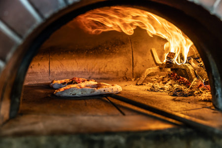 Traditional oven for baking pizza with burning wood and shovel. The cook rotates the pizza in the oven to ensure even baking.の写真素材