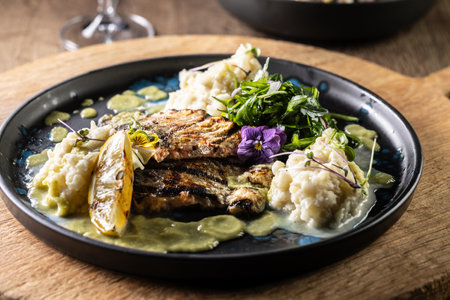 Grilled trout fillet with mashed potatoes and lemon sauce on a restaurant plate.の写真素材