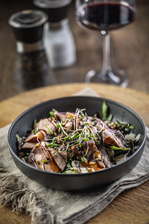 Roast beef salad with herbs and balsamic sauce in the style of a bowl on a restaurant table.の写真素材