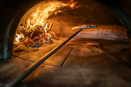 Traditional oven for baking pizza with burning wood and shovel. Neapolitan pizza is finished on a shovel in a brick oven.の写真素材