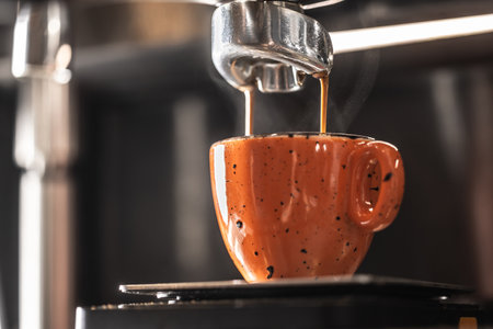 The coffee machine makes coffee into an orange cup.の写真素材