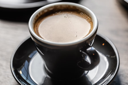 Traditional espresso coffee in a black cup on a table in a cafe.の写真素材