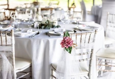 A wedding table covered with a white tablecloth, decorated with flowers, candles, glasses and cutlery.の写真素材