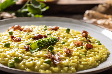 Italian saffron risotto with peas and bacon creatively served on a plate.の写真素材