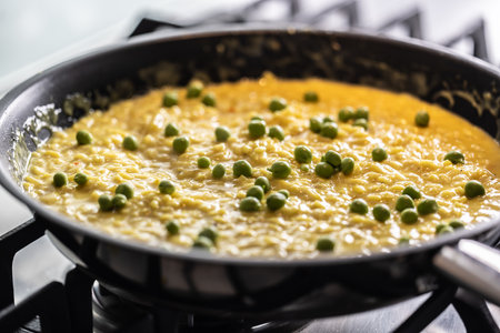 Saffron risotto with peas cooked in a pan on a gas stove.の写真素材