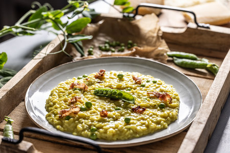 Italian saffron risotto with peas and bacon creatively served on a plate.の写真素材