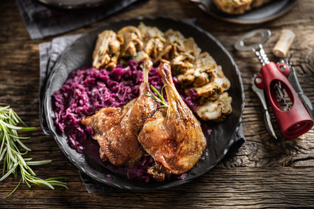 Portion of roast duck leg red cabbage homemade dumplings on plate and red wine on the background.の写真素材