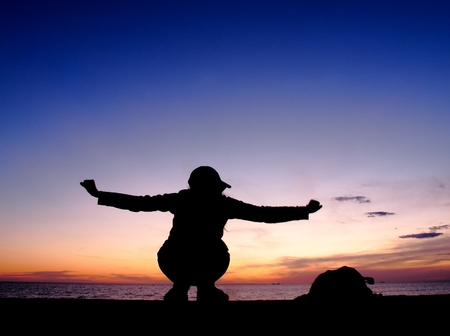 silhouette woman sit at sea , sunset lightの写真素材