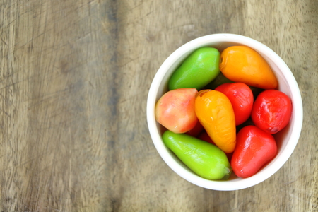 DELETABLE IMITATION FRUITS (KANOM LOOK CHOUP) in white small bowl on wood table top view have copy space for put text, colorful handmade dessert, mold bean to many shape like fruits and cover by jellyの写真素材