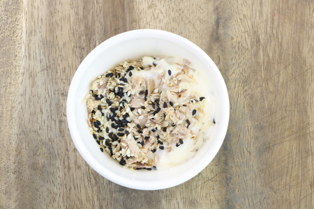Tuna cream salad with sesame in white bowl for eat with fresh vegetable salad on wooden table backgroundの写真素材