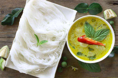 Top view of green curry fish ball served with Thai rice vermicelli in white bowl on wood table, look delicious.の写真素材