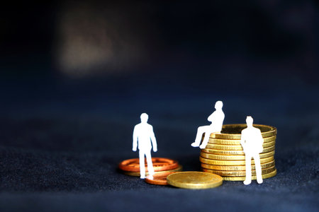 team of white miniature business people sitting and standing on golden coins pile on black background, concept growing golden coins for businessの写真素材
