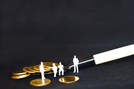 team of white miniature business people sitting and standing on golden coins pile on black shovel, on black background have copy space for put text, concept digging golden coins for businessの写真素材