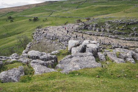 The dramatic fissured limestone pavement geology high above Malham Cove set against green fields and...