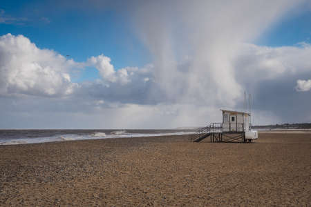 Hail storm passing over lifeguard hut on a deserted beach on a cold windy winters day, Gorleston-on-Sea, near Great Yarmouth, Norfolk, UKの写真素材