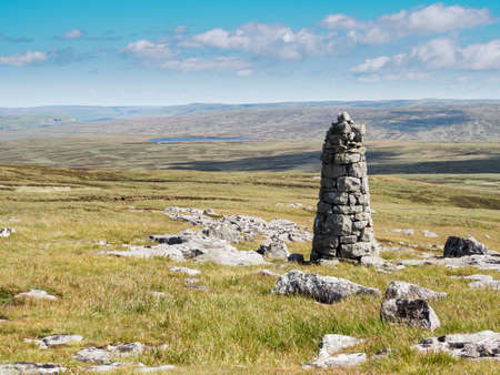 View over a tall cairn to Birkdale Tarn from a collection of stones known as the Millstones, Yorkshire Dales National Park, UKの写真素材
