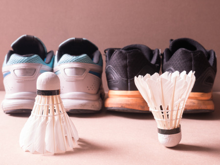 sports set of black orange sport shoes and blue sport shoe and shuttlecocks issymbolic of man and women on sport background in concept family activityの写真素材