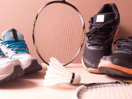 sports set of black orange sport shoes and blue sport shoe and shuttlecocks with two badminton racket on sport background in concept family activityの写真素材