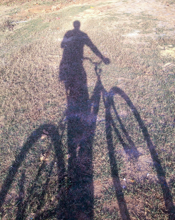 someone with bicycle shadow on groundの写真素材