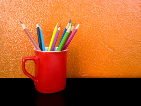 pencil color in red cup on orange backgroundの写真素材