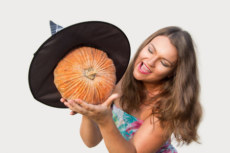 Beautiful girl holding halloween pumpkin with witch hat on white background