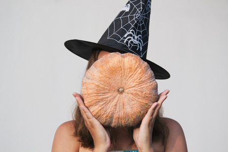Girl in Halloween witch hat with pumpkinの写真素材