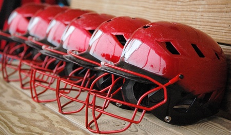 A row of batting helmets sit on the bench ready for action