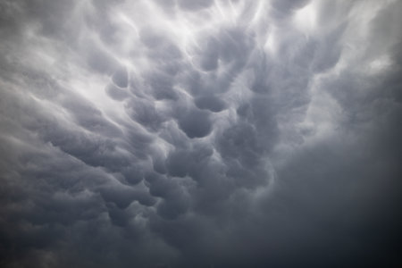 A striking formation of mammatus clouds looms in the sky, preceding a thunderstorm. These distinct,...