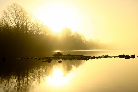 sunrise behind golden fog on rivers edgeの写真素材