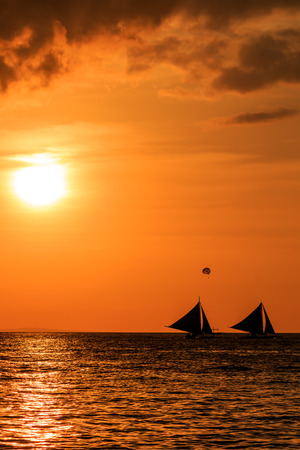 Traditional sailing boats in silhouette at sunsetの写真素材