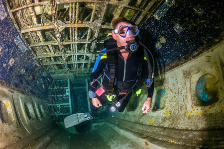 A SCUBA diver explores the upturned cabin of an underwater aircraft wreckの写真素材