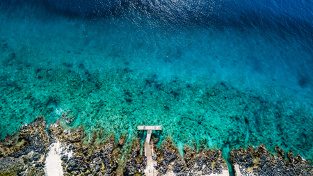 Aerial view of a small dock leading onto a tropical coral reef in crystal clear blue waterの写真素材
