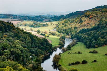 A river with farmland and a forest during the autumnの写真素材