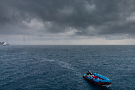 Small boat in a rough ocean and tropical thunderstormの写真素材
