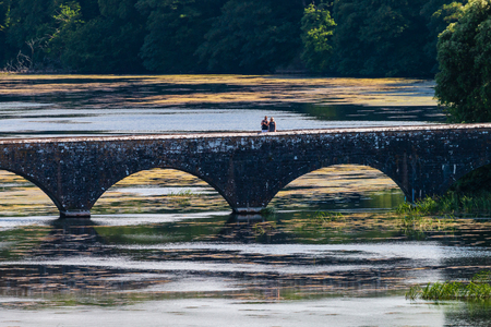 Aerial drone view of an old bridge spanning a beautiful lake in a rural area of Walesの写真素材