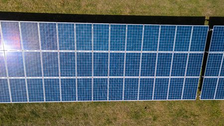 Aerial drone view of lines of solar panels in a field at a solar farm in South Wales, UK