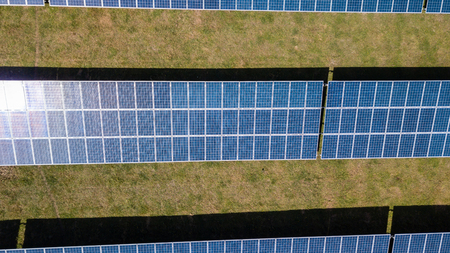 Aerial drone view of lines of solar panels in a field