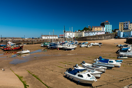 Colorful fishing and pleasure boats resting on the sand at a harbor during low tide on a sunny dayの写真素材