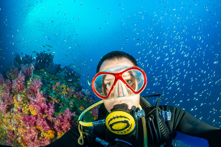 A SCUBA diving posing underwater next to colorful, fragile soft corals on a tropical reefの写真素材
