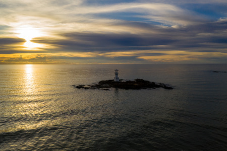 Aerial view of a lighthouse and beautiful tropical sunset over the oceanの写真素材